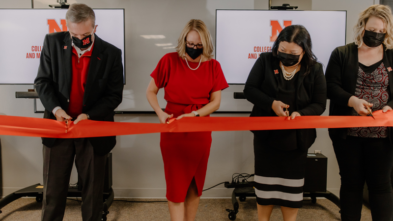 four people cutting a ribbon