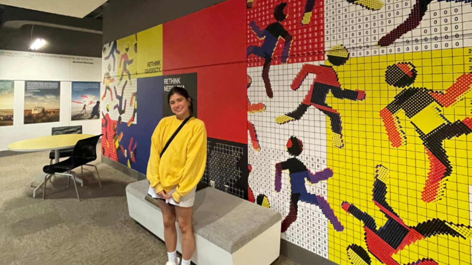 Student stands in front of mural