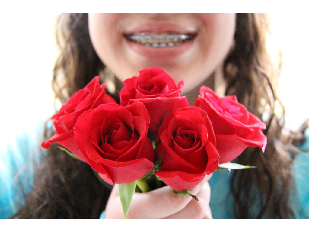 Girl with braces smiling while holding roses