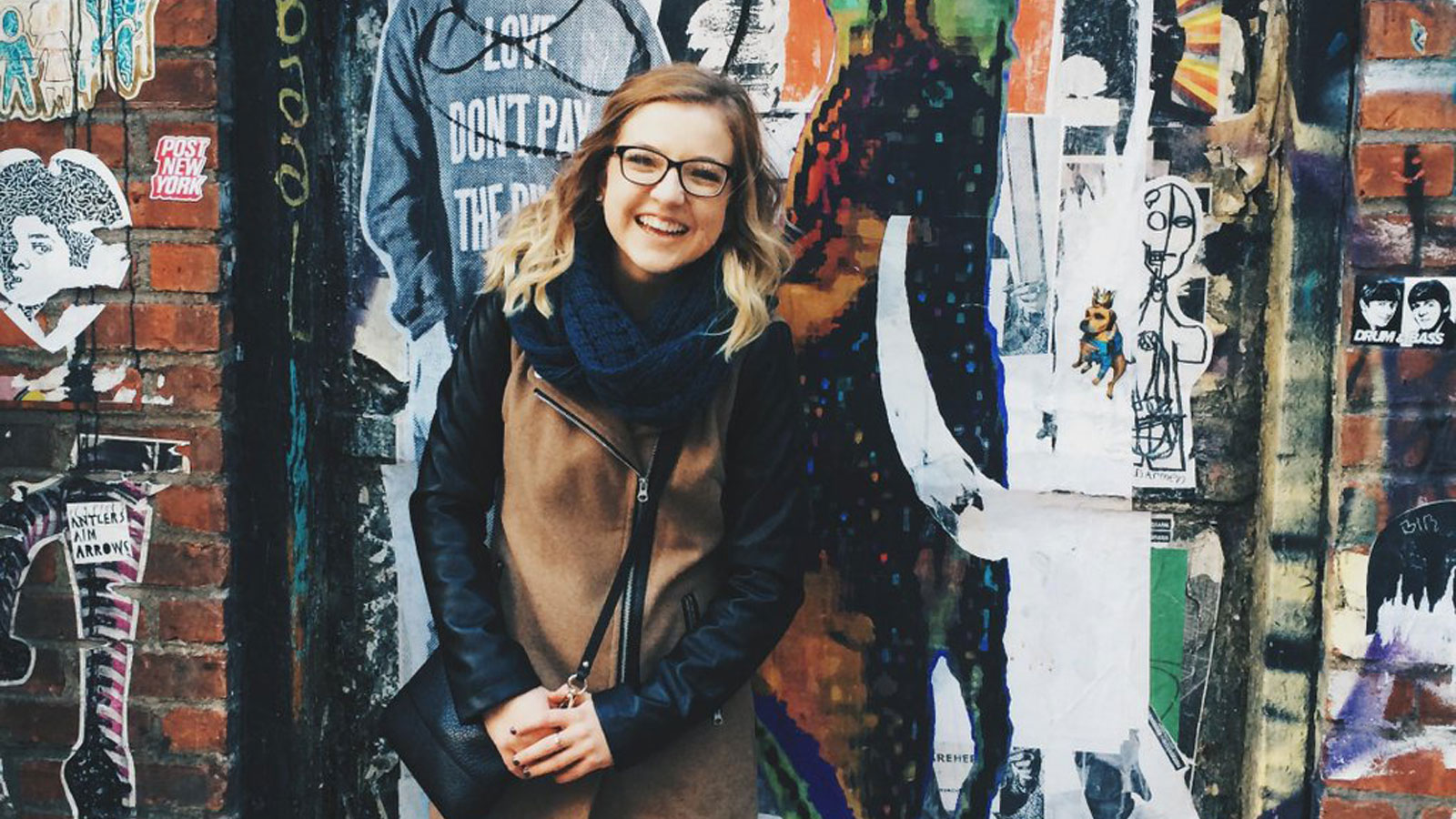 Bailey Williams stands in front of a piece of street art