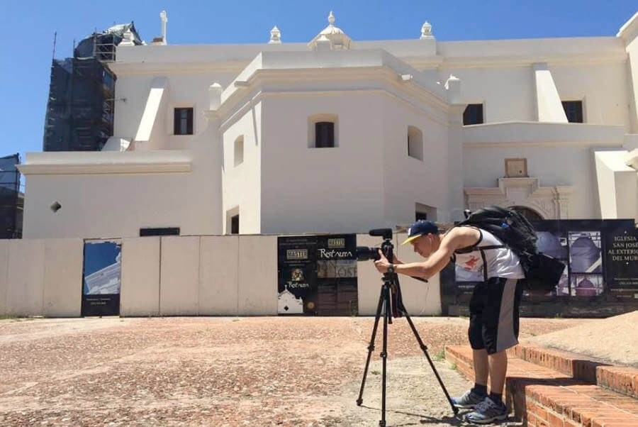 Student focuses camera while standing in front of building