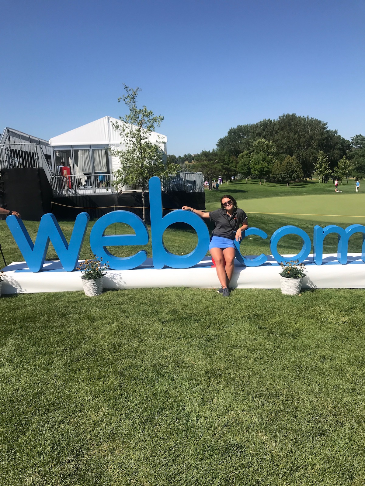Logan John takes a break from working at the Pinnacle Bank Championship Golf Tournament, one of Hurrdat’s clients, to pose with a statue of one of the sponsors, web.com. (Photo by Reilly Nelson)