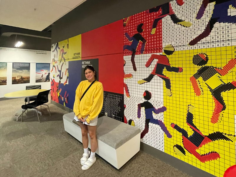 Ashley posing by the mural featuring her design