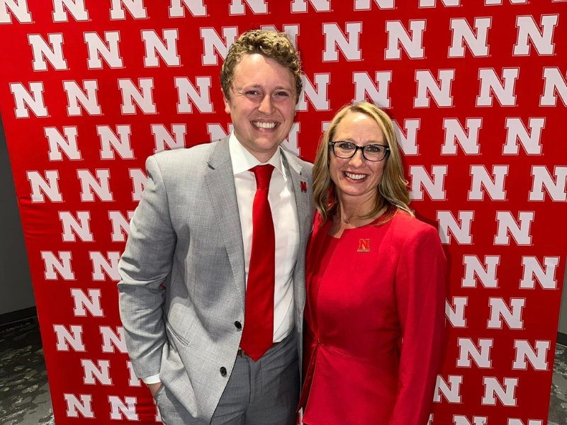 Photo of man and women in front of Husker N backdrop