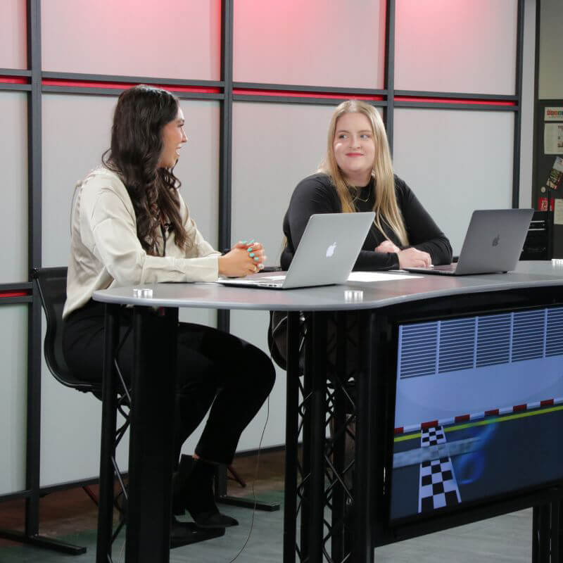 Students sit at broadcast desk