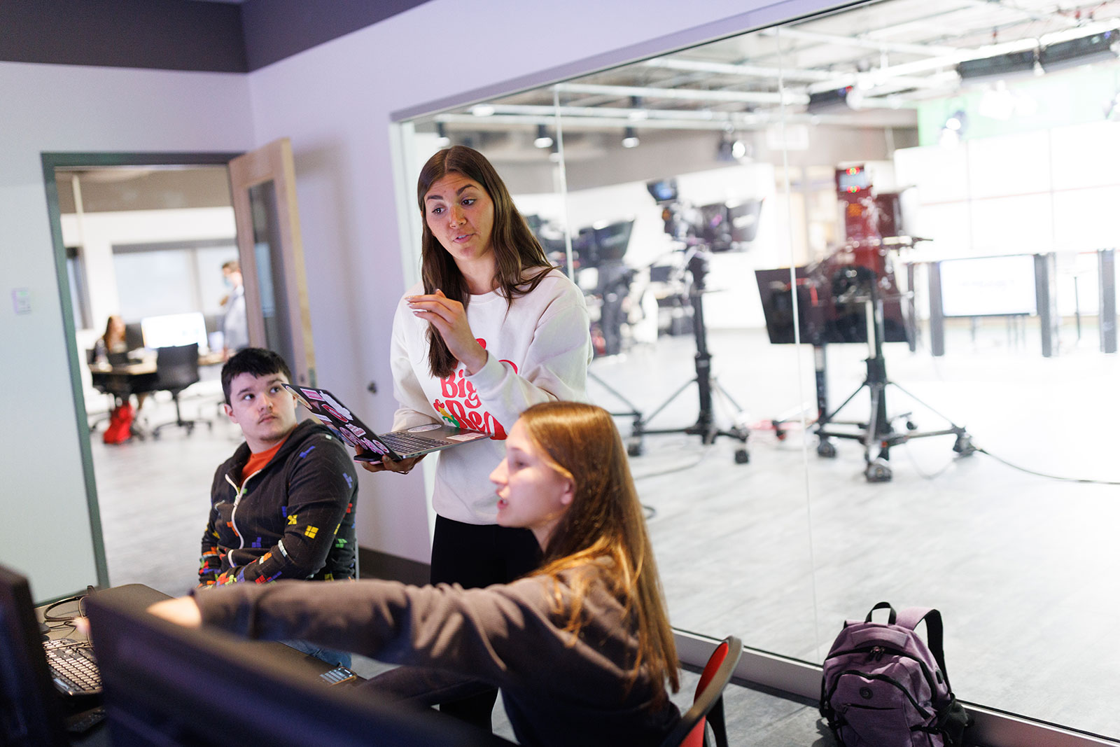 Three people point at a computer screen