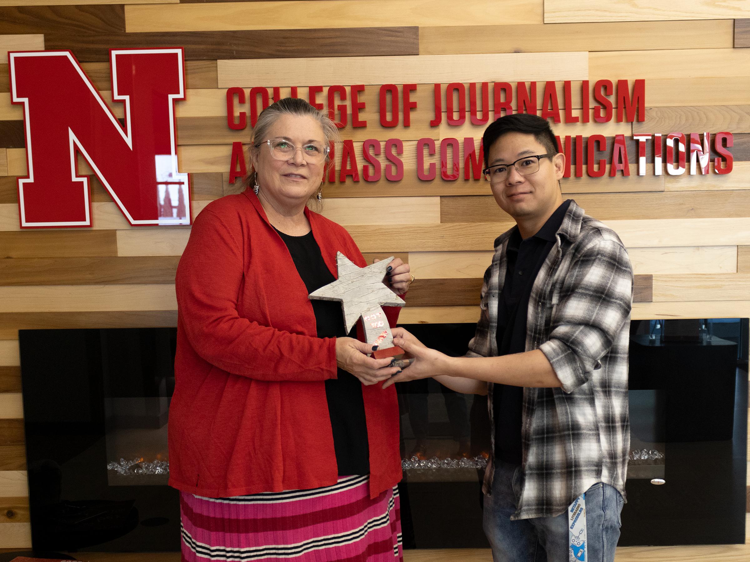 Two people stand holding award