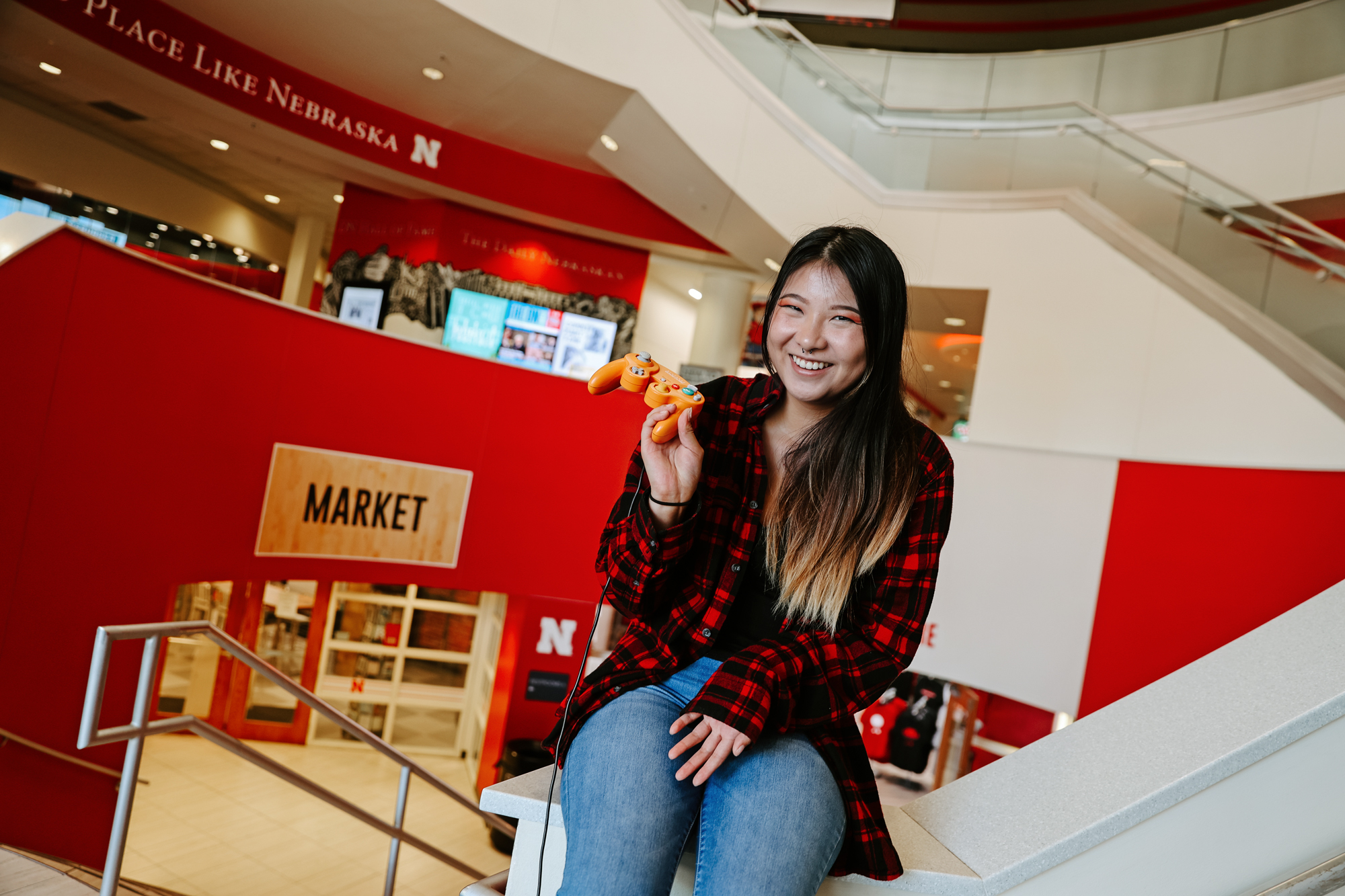 woman sits on a set of stairs holding a gaming controler