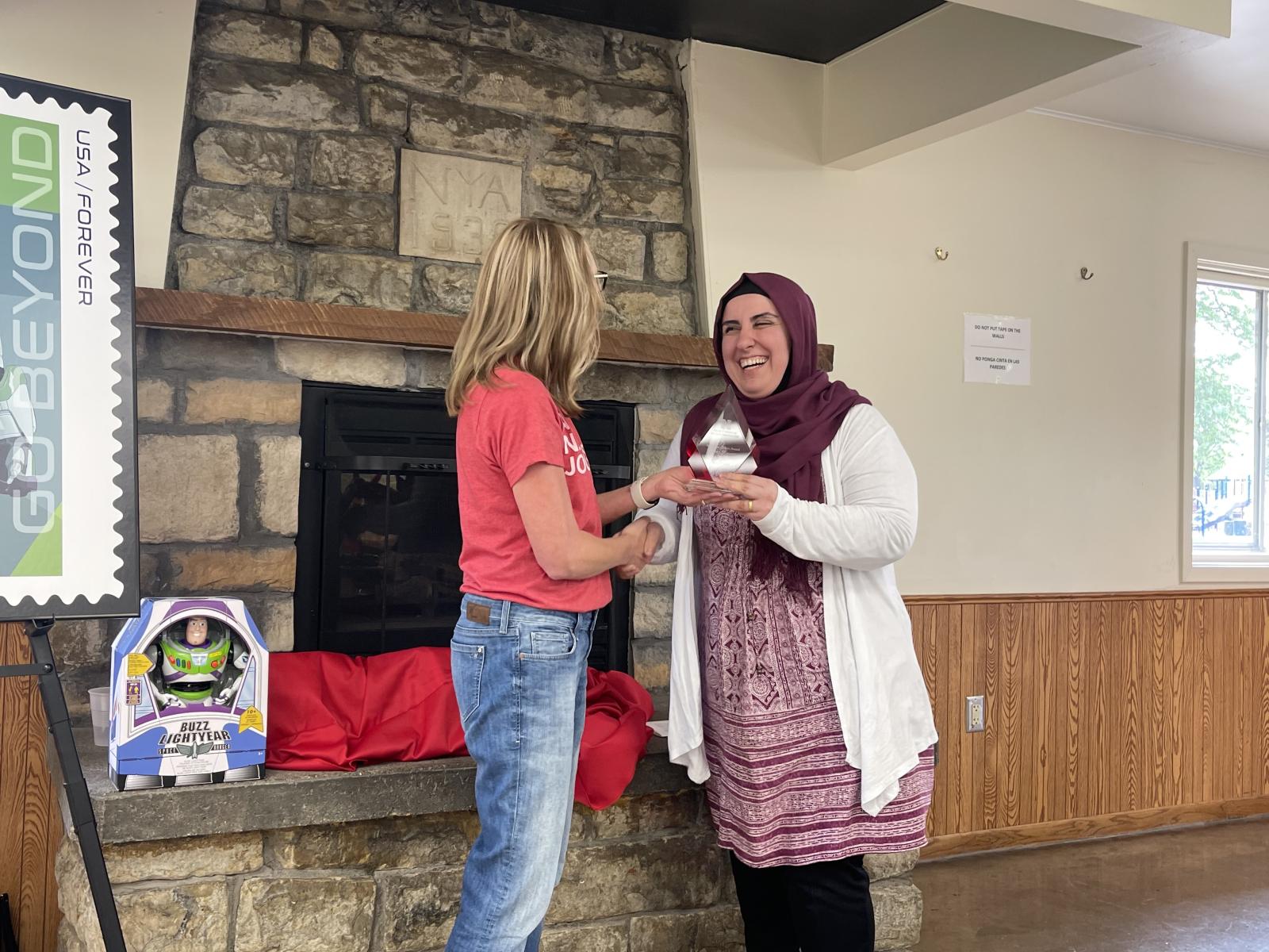 Staff Excellence Award recipient Karez Hassan, academic adviser, smiles while receiving her award from CoJMC Dean Shari Veil.