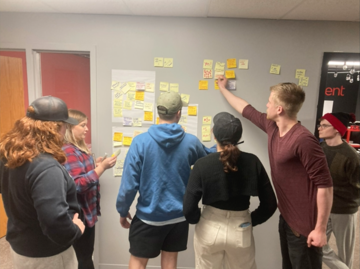 students putting sticky notes on a wall