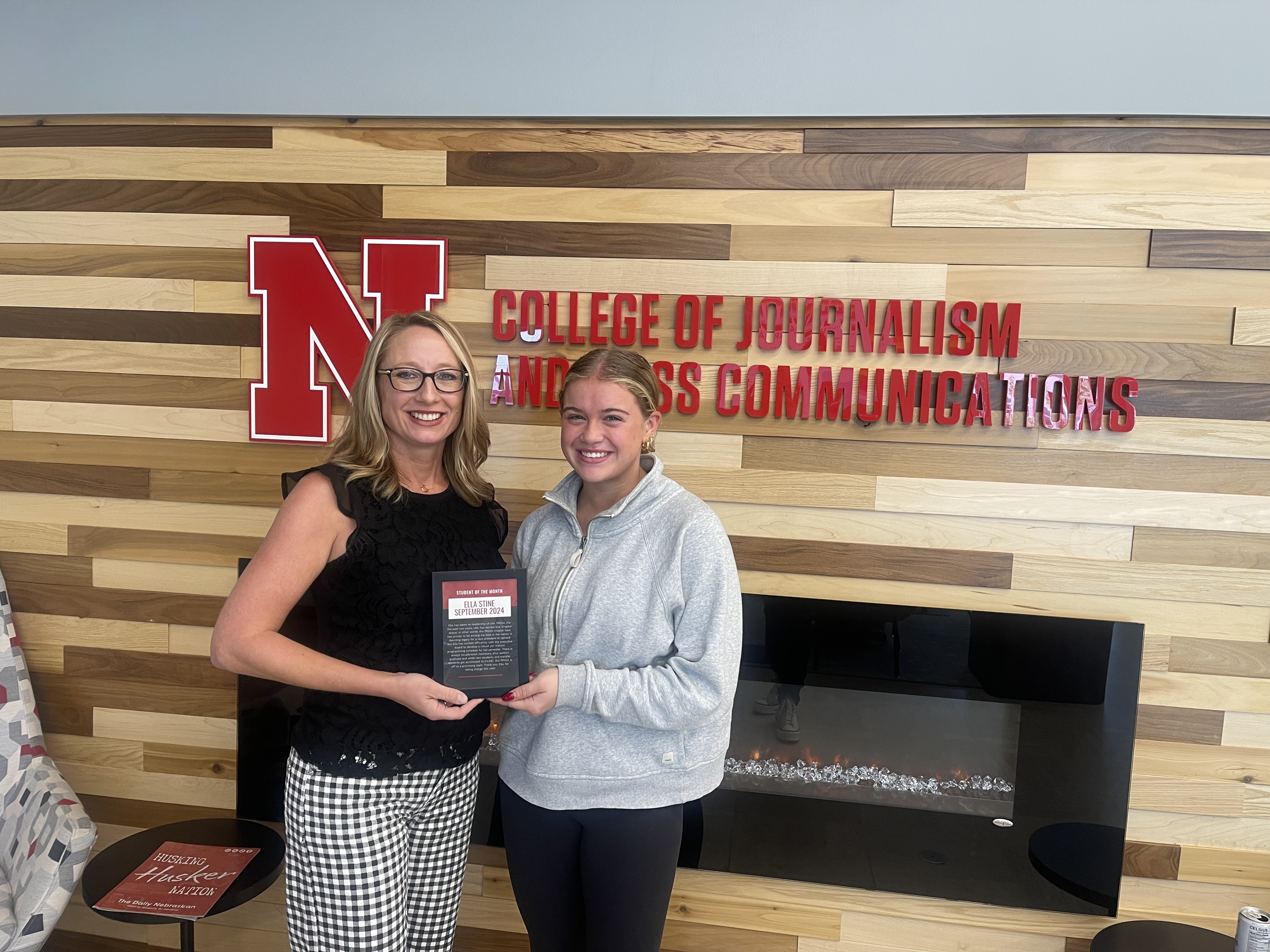 Two people pose holding an award