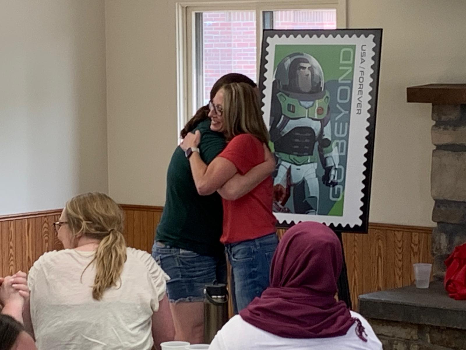 Dean’s Pretty Awesome Award recipient Tiffany Groteluschen, administrative coordinator, embraces CoJMC Dean Shari Veil.