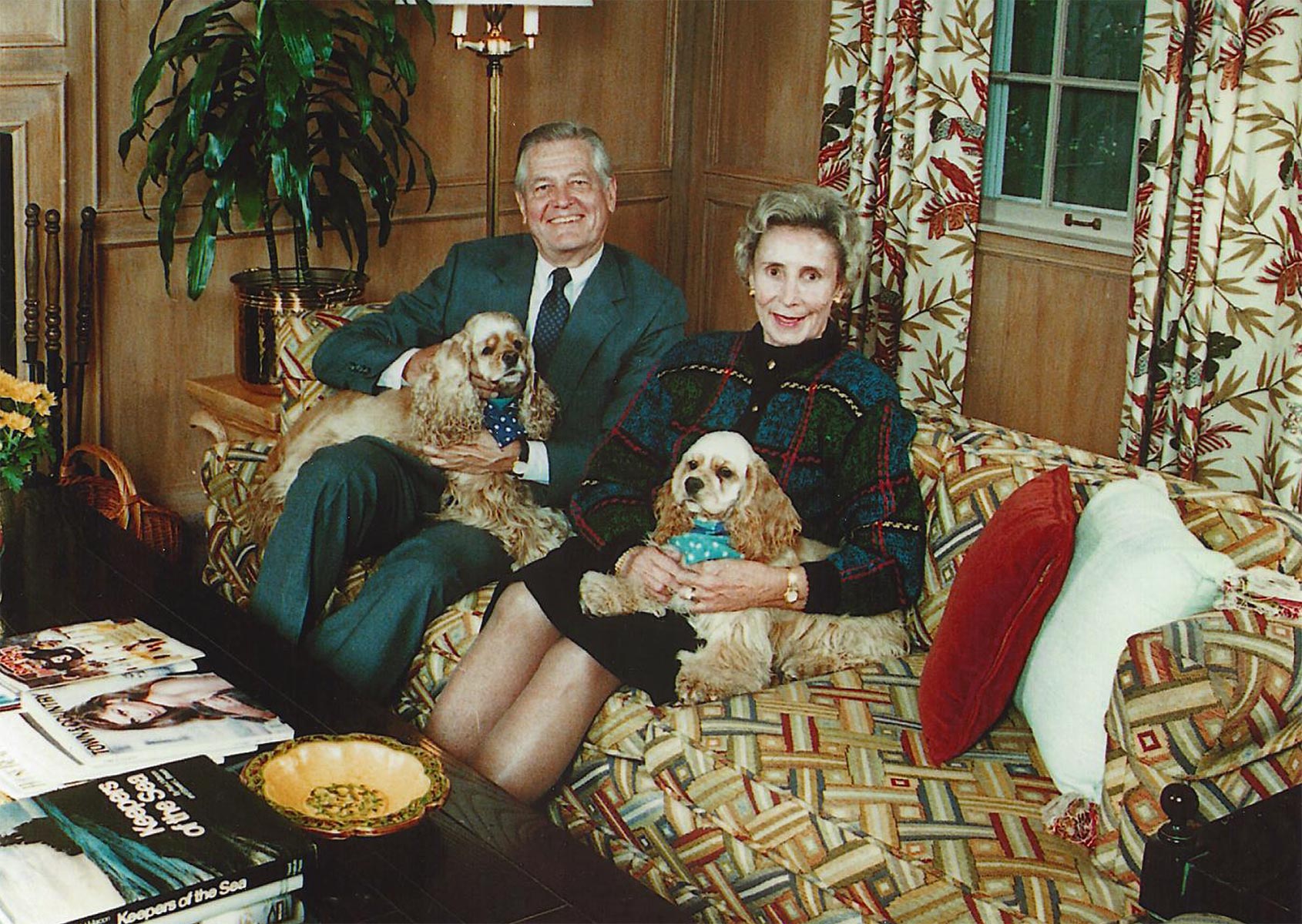 A man, a woman and two dogs sit on a couch