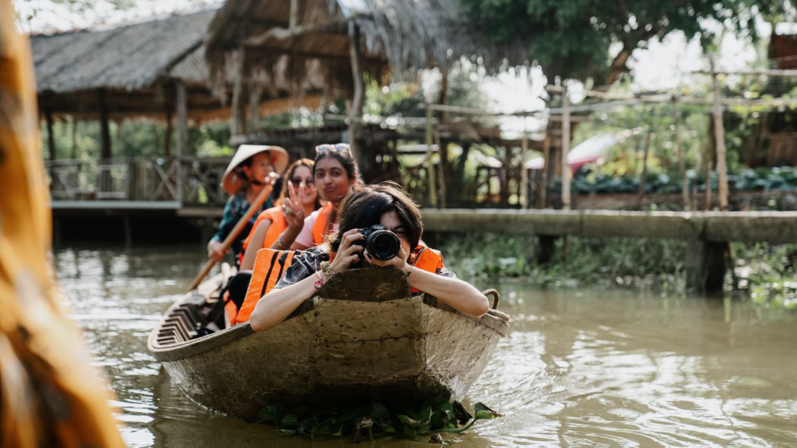 students sitting on a boat while one takes a picture from her camera