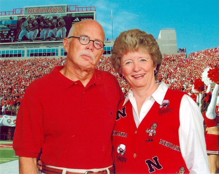 A man and a women pose in red shirts