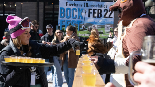 Holly Sousek loads apple pie shots onto a shotski being held by her husband, Tony, at BockFest in Lincoln, Nebr. on Saturday, February 22, 2025. Tony is a woodworker who handcrafted each of the shotskis used at the event.