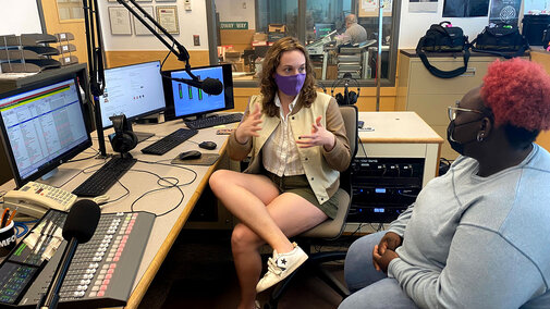 Two women talk to each other in a radio station