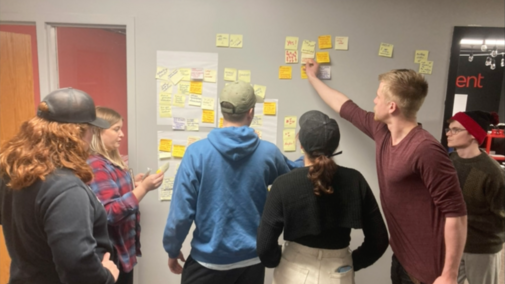 students putting sticky notes on a wall