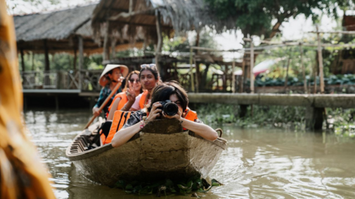 Students riding in a boat while one student is taking a picture