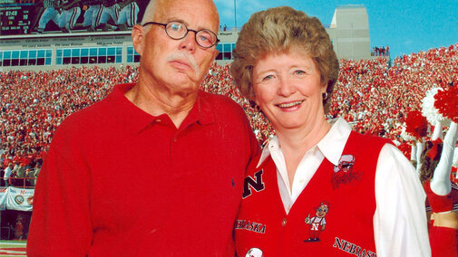 A man and a women pose in red shirts