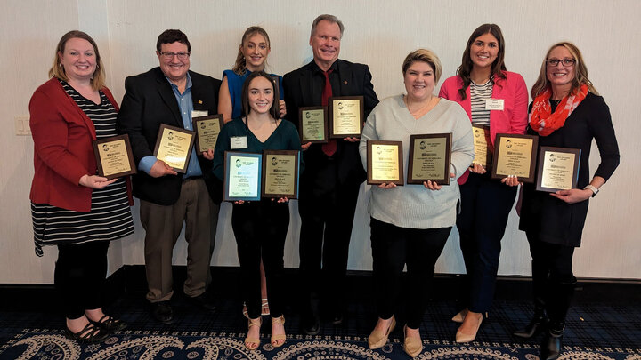 Two men and six women hold plaques.