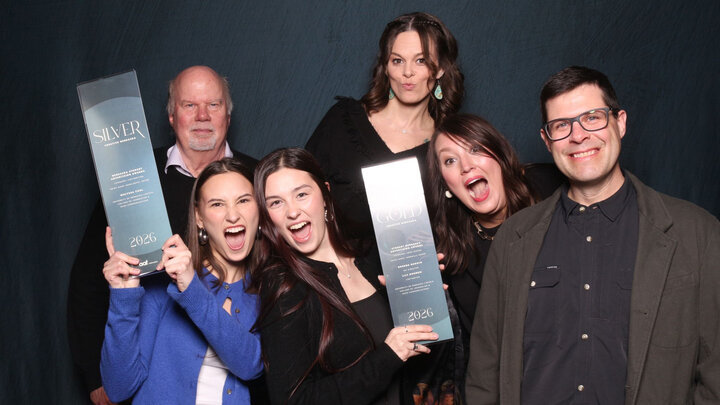 Four women and two men pose with two awards.