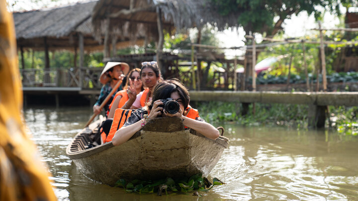 Mari Pilling, a senior broadcasting major, shoots photos from the bow of a boat while traveling down a river in Cần Thơ, Vietnam, on Jan. 16. Students traveled to Vietnam to gather content as part of a Global Eyewitness project offered through the College of Journalism and Mass Communications.