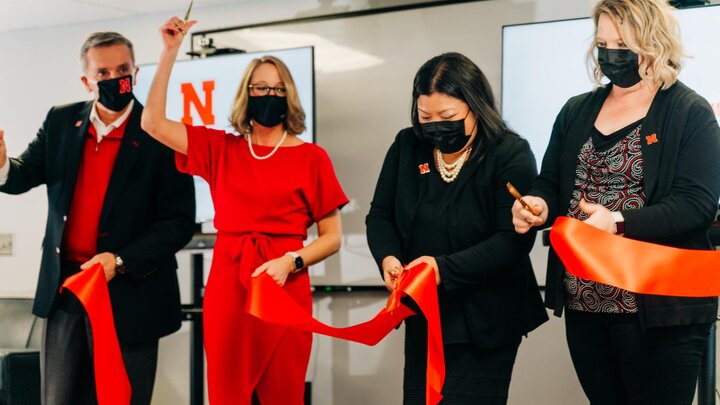 Four people cut a red ribbon