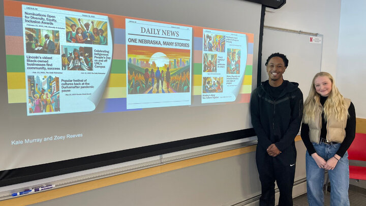 students standing beside their presentation on a screen