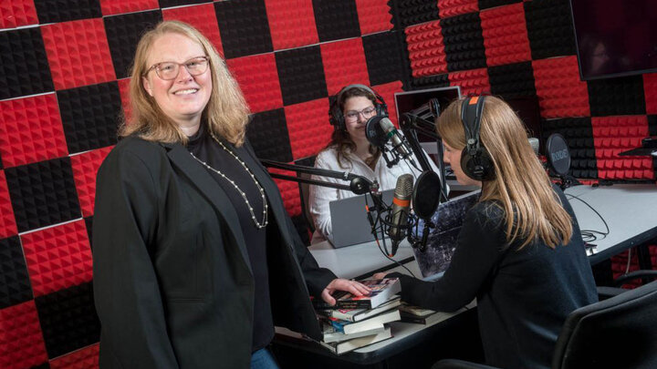 Professor Kelli Boling standing in front of two students recording a podcast