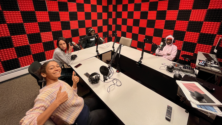 Students sit around a table in the podcasting studio