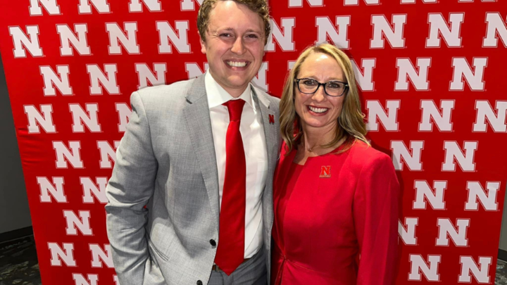 Photo of man and women in front of Husker N backdrop