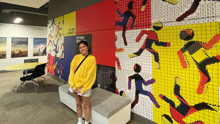 Ashley posing by the mural featuring her design