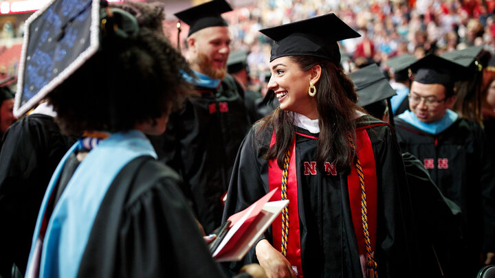 Student in cap and gown in crowd