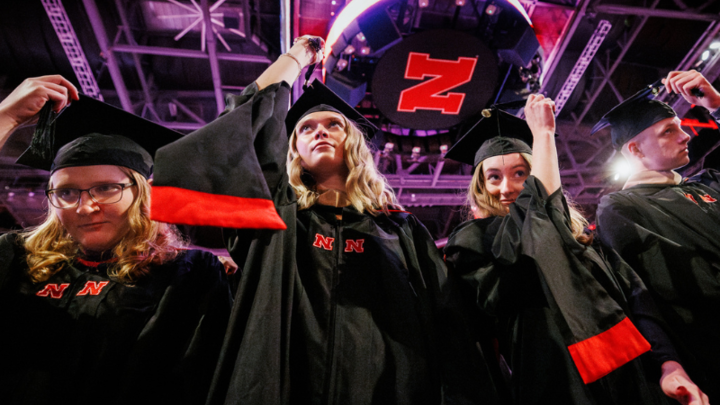 four students move the tassles on their graduation cap