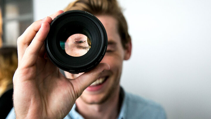 Man looks through a camera lens