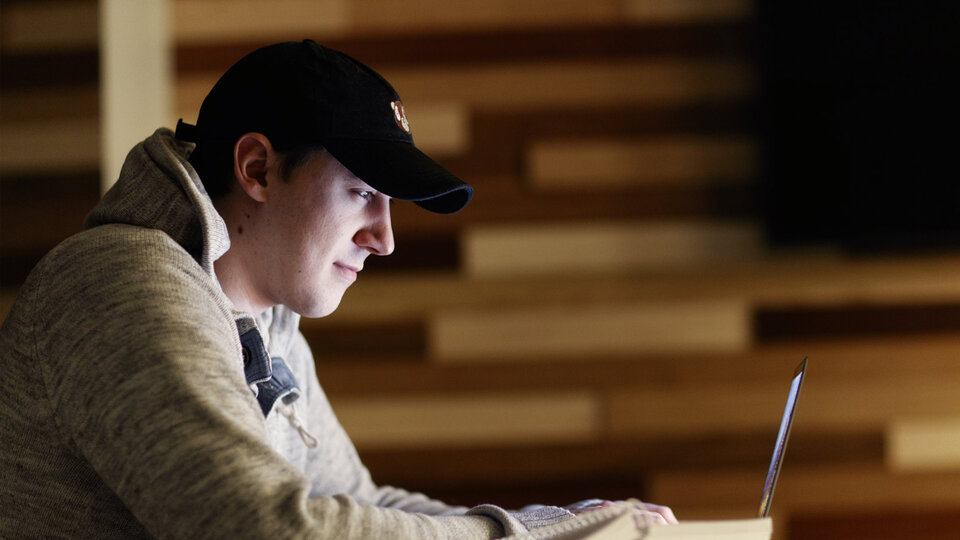 student in Andersen Hall on laptop