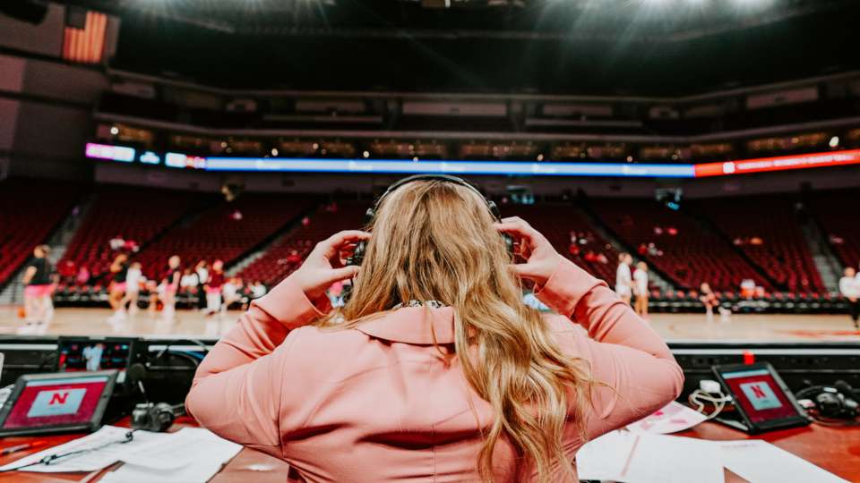 Woman wearing headphones with basketball court behind her