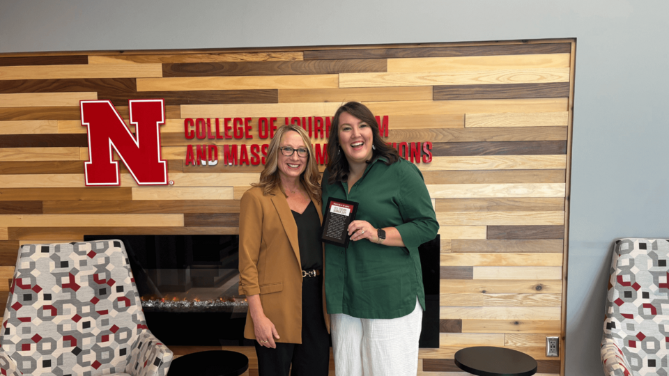 Assistant Professor of Practice Elle Stecher (right) accepts the Summer Professor of the Month Award from Dean Shari Veil (left).