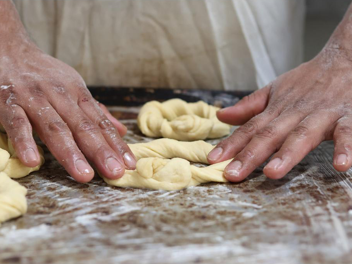 Two hands knead dough on a table