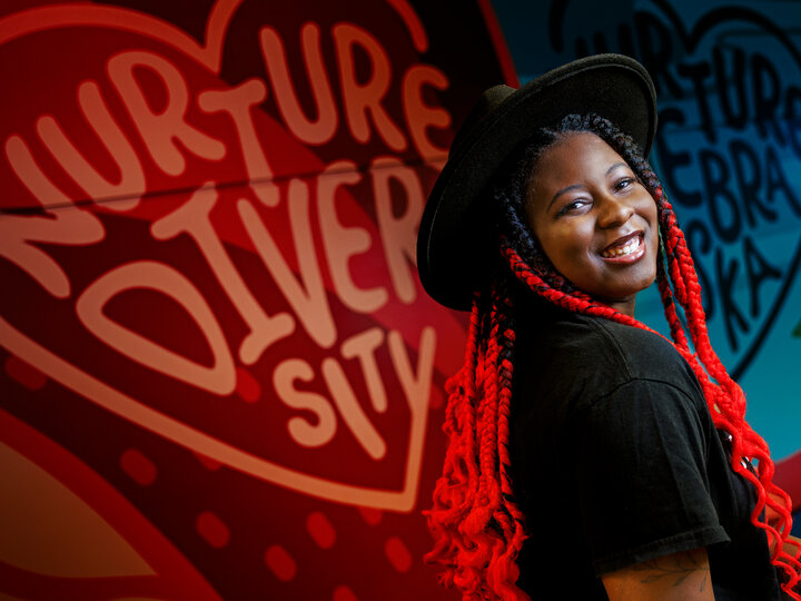 Alana Ross smiles for a photo in front of a mural in Anderson Hall.