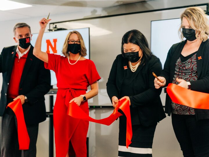 Four people cut a red ribbon