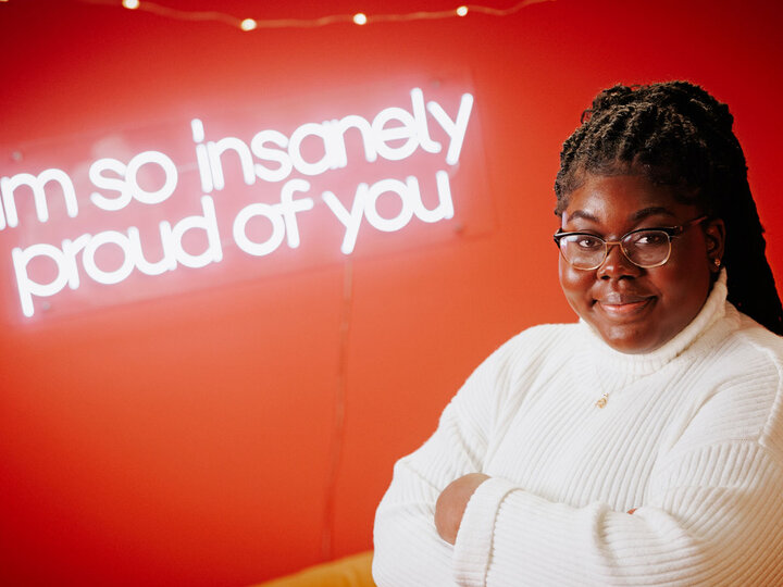 Woman stands in front of sign that reads "I'm so insanely proud of you."