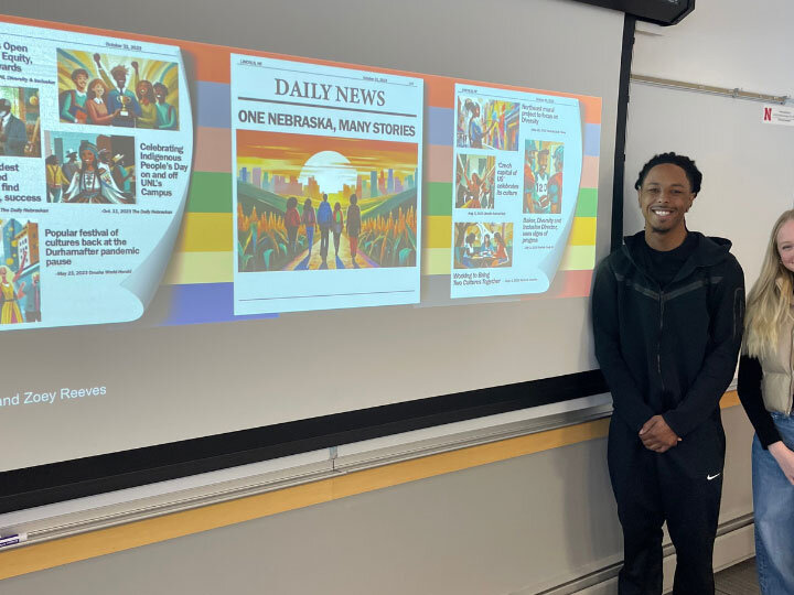 students standing beside their presentation on a screen