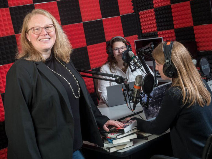 Professor Kelli Boling standing in front of two students recording a podcast