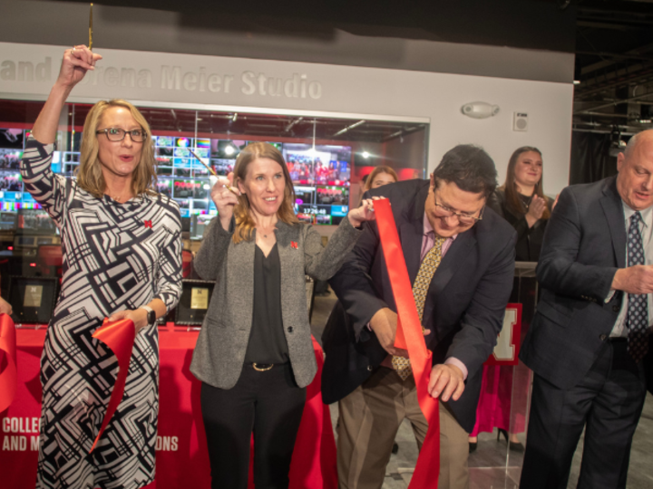 Five people cut a red ribbon