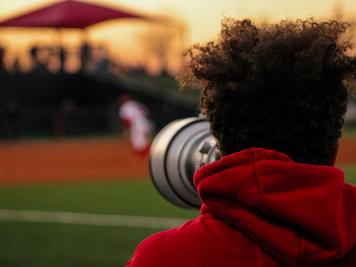 Back of  a man's head holding a large camera lens