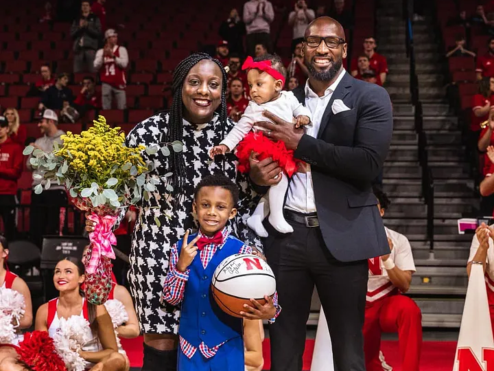 Two adults and two children stand in the middle of a basketball court