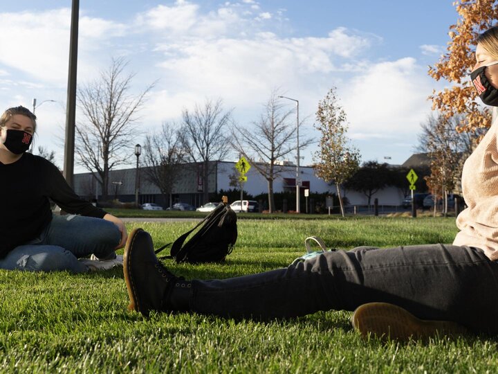 Two women sit in the grass