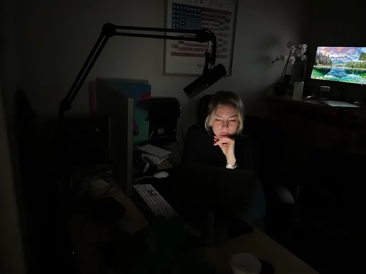 women sits at a desk in a dark room 